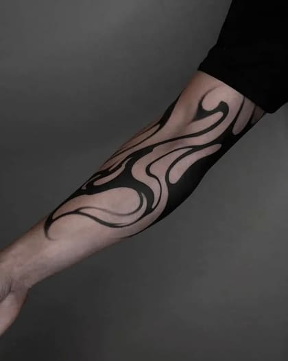 Tatuagem abstrata blackwork no braço com formas fluidas e orgânicas em preto sólido.