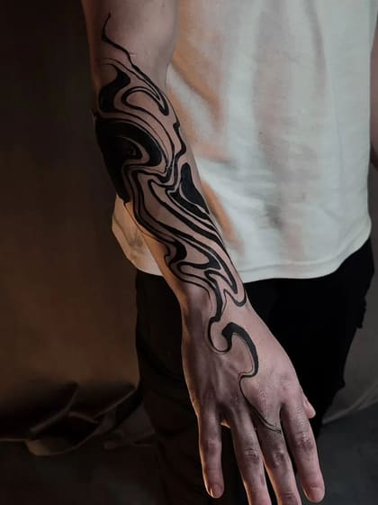 Tatuagem abstrata fluida em blackwork no braço e mão de um homem, com formas orgânicas e linhas pretas.
