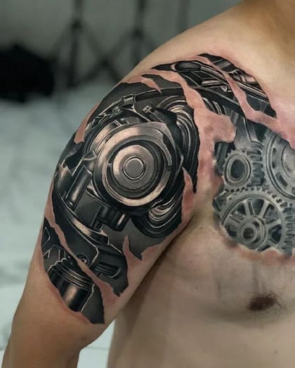 Tatuagem biomecânica realista no ombro e peito, mostrando engrenagens e pistões de metal sob pele rasgada, em tons de cinza e preto.