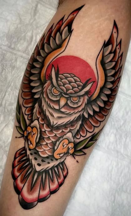 Tatuagem de coruja em estilo Old School com asas abertas e sol vermelho ao fundo, em cores vibrantes.
