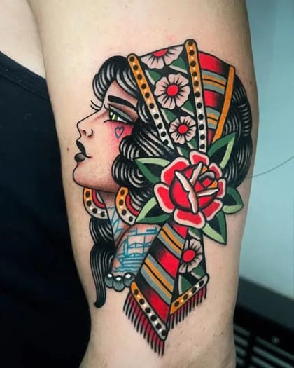 Tatuagem Old School de uma dama com lenço florido e rosa vermelha no braço, estilo tradicional vibrante.