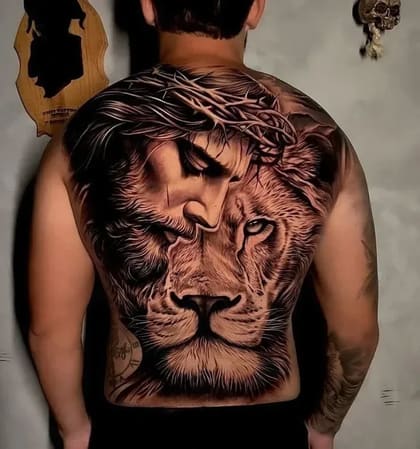 Tatuagem de realismo preto e cinza nas costas, retratando Jesus Cristo com coroa de espinhos e um leão majestoso.