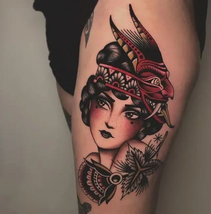 Tatuagem Old School colorida de mulher com máscara de demônio Hannya e elementos florais na coxa.