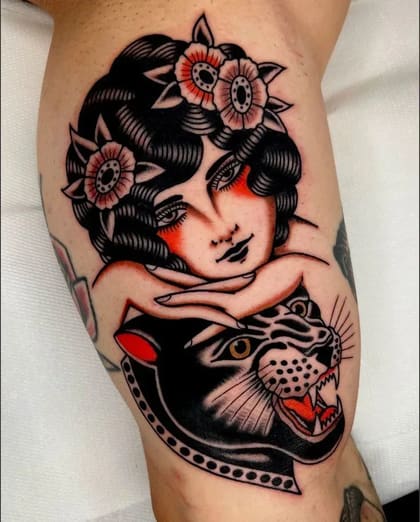 Tatuagem Old School colorida de mulher com flores e pantera preta rosnando no braço.