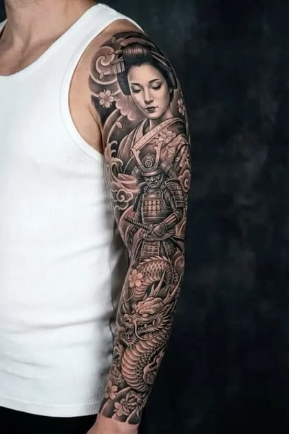 Tatuagem oriental black and grey de braço inteiro com geisha, samurai e dragão em estilo japonês tradicional.