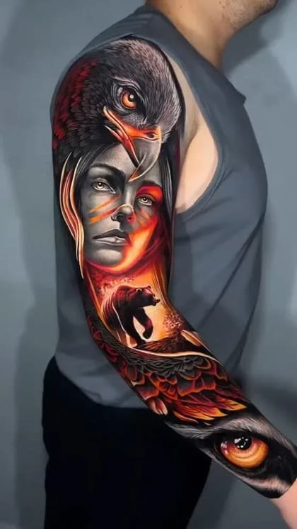 Tatuagem de braço completo em realismo colorido com águia, rosto feminino, urso e olho, em tons de vermelho e laranja.