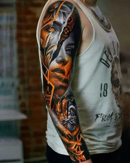 Tatuagem de sleeve em realismo colorido com rosto feminino dividido em tons vibrantes e preto e cinza, coração anatômico acorrentado e detalhes florais.