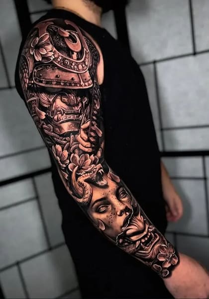 Tatuagem de braço completa em estilo oriental black and grey com capacete samurai, máscara Hannya, rosto de Medusa e serpente entre flores.