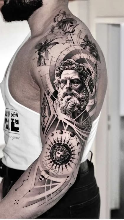 Tatuagem de braço completo masculina em realismo preto e cinza, com busto de Zeus, cabeça de Medusa e elementos geométricos.